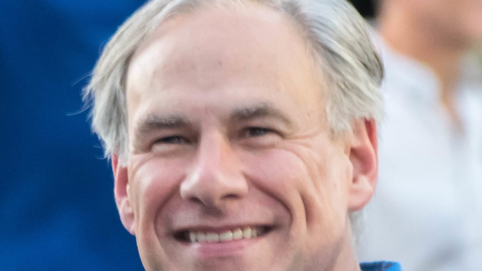 A smiling man with gray hair in a blue button-down shirt, photographed outdoors.